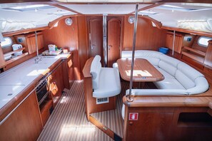 A compact boat interior with a dining area, a small kitchen, and a seating area. - Sun-kissed Sailing Adventure in Split-Dalmatia, Croatia (Seget Donji)