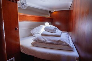 A compact, well-lit cabin with a single bed, a wooden headboard, and a ceiling fan. - Sun-kissed Sailing Adventure in Split-Dalmatia, Croatia (Seget Donji)