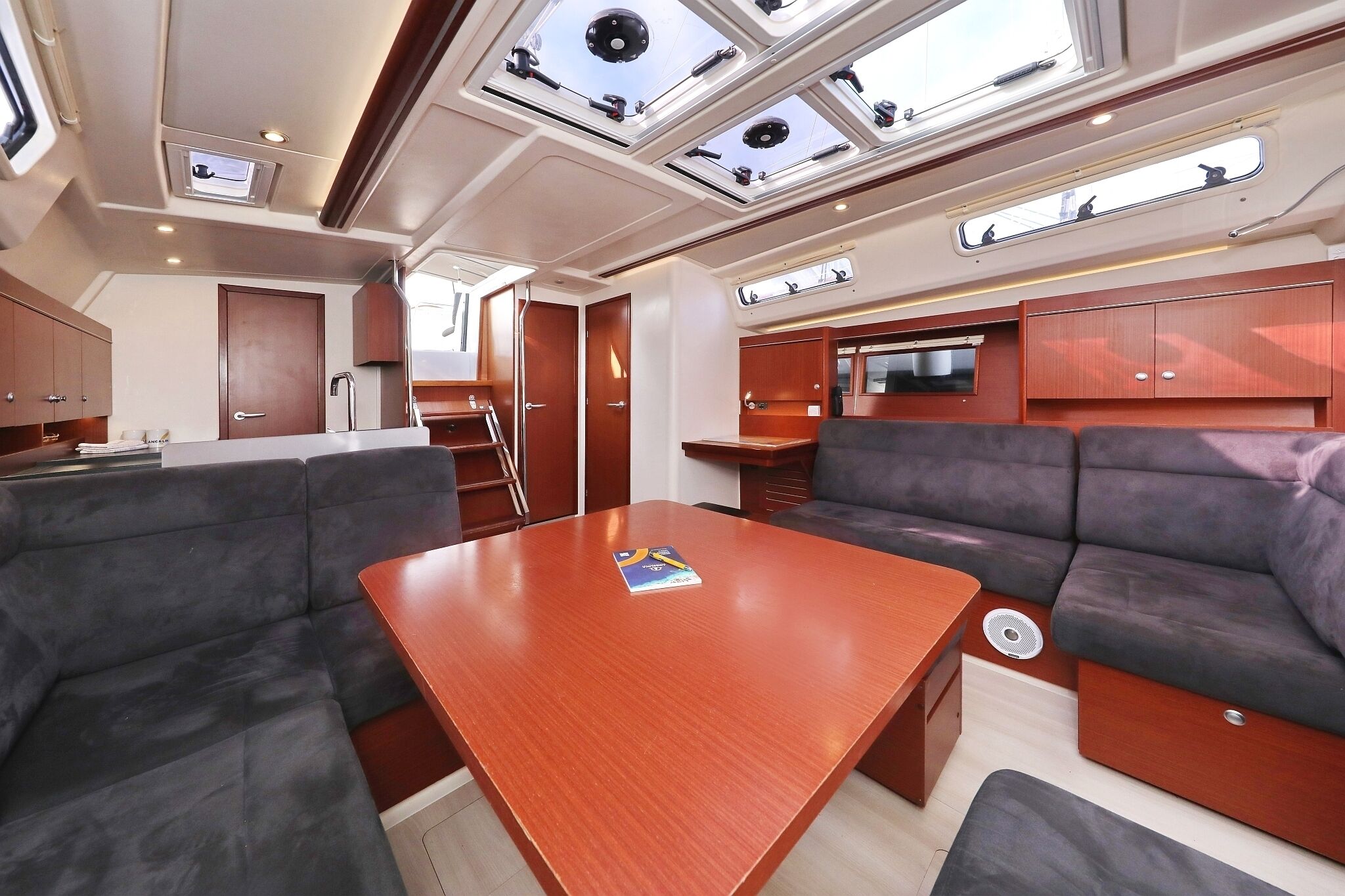 A compact interior with a central table, cushioned seating, and skylights.