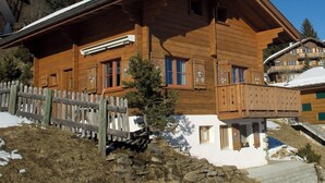 Un chalet en bois doté d’un balcon, d’un escalier en pierre et d’une clôture en bois.