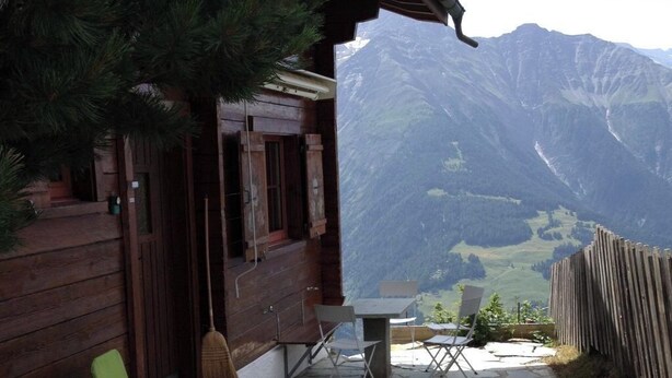 Une cabane en bois avec un patio en pierre, un espace salon extérieur et une vue sur la montagne.