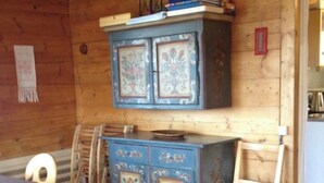 Une pièce avec un plafond en bois, un buffet bleu orné de motifs complexes, une chaise en bois et une table.