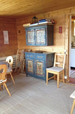 A room with a wooden ceiling, a blue cabinet with ornate designs, a wooden chair, and a table. - Sunneschy 1. OG Süd Appartement/Fewo, Dusche, WC 3 Zimmerwohnung, 6-Betten by Interhome (Riederalp)
