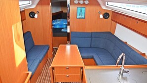 A compact interior with a sofa, a small table, a sink, and a window. - Sun-Kissed Sailing Adventure in Split, Croatia (Kaštel Gomilica)