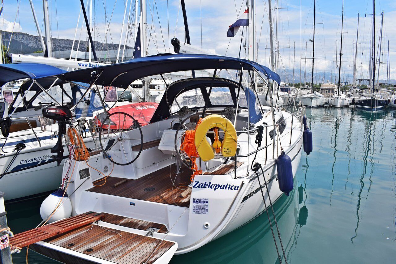 A boat docked at a marina with a wooden deck, a steering wheel, and a life buoy.