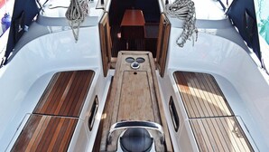 A boat's deck with a central wooden table, two side seating areas, and a small enclosed space with a table and chairs. - Sun-Kissed Sailing Adventure in Split, Croatia (Kaštel Gomilica)