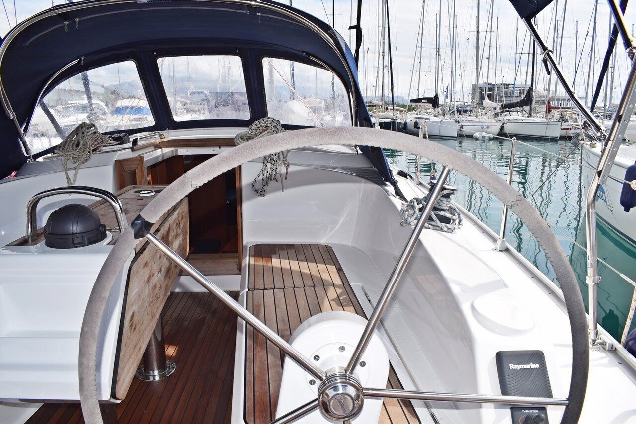 Cubierta de barco con timón, suelo de madera y sistema de navegación Raymarine.
