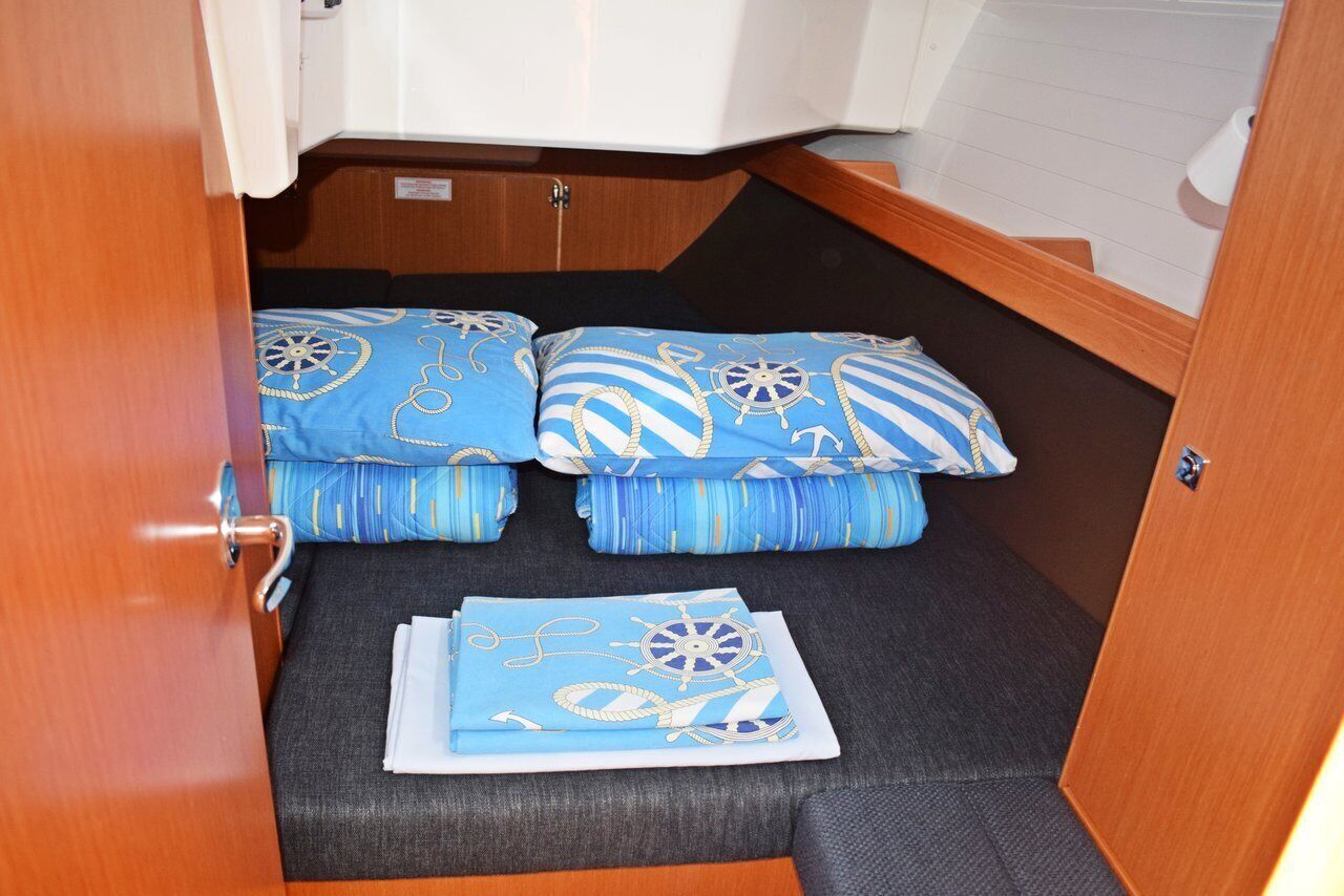 Um espaço compacto para dormir, com cama, almofadas e um cobertor dobrado.