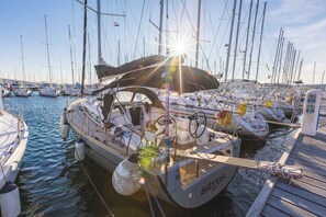 A marina with multiple sailboats docked, a clear sky, and a sun shining through the masts. - Sun-Kissed Sailing Adventure in Northern Croatia (Punat)