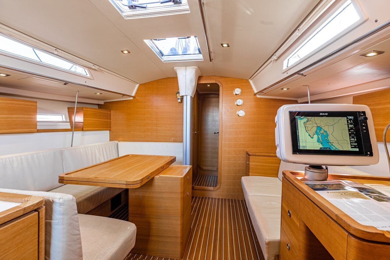 A boat interior with a dining area, a control panel, and a small window.