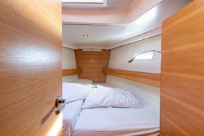 Een compact vakantiehuisje met een enkel bed, houten lambrisering en een klein raam.