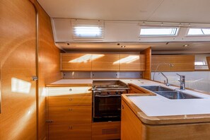Een kleine keuken met houten keukenkastjes, een fornuis en een spoelbak.
