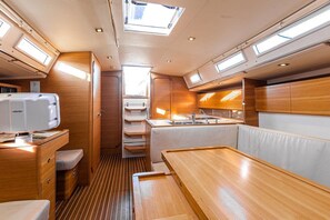 A compact, well-lit interior with a kitchenette, seating area, and a window providing natural light. - Sun-Kissed Sailing Adventure in Northern Croatia (Punat)