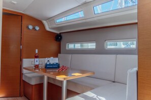 Et kompakt indrettet rum med et bord, siddepladser og en flaske vin.