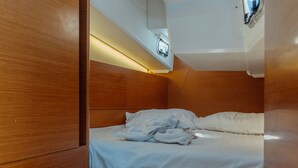 Et lille, træindrettet værelse med seng, et lille bord og en lampe i loftet.