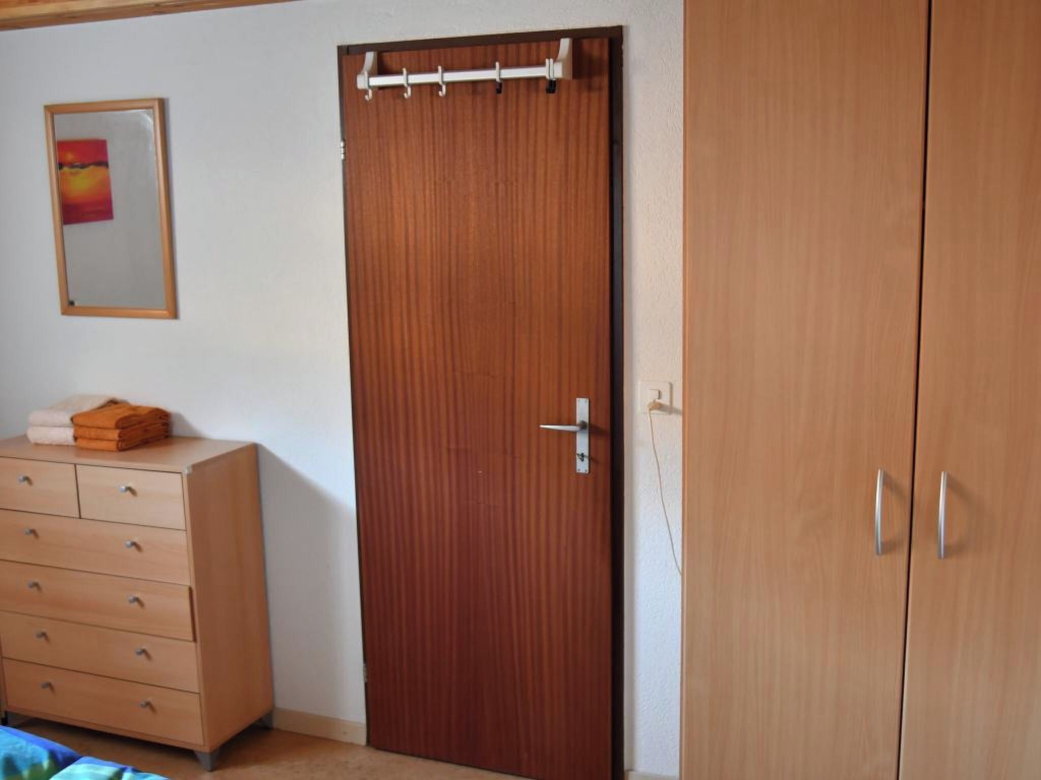 Un dormitorio con un armario de madera, un aparador y una cama.