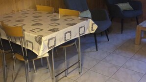 Un espace repas comprenant une table et des chaises, des murs en bois et un sol carrelé.