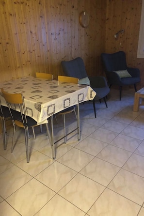 Ein Essbereich mit Tisch und Stühlen, Holzwänden und einem Fliesenboden.