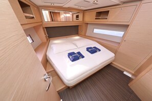 Una cabina compatta con un letto singolo, spazio contenitori integrato e una piccola finestra.