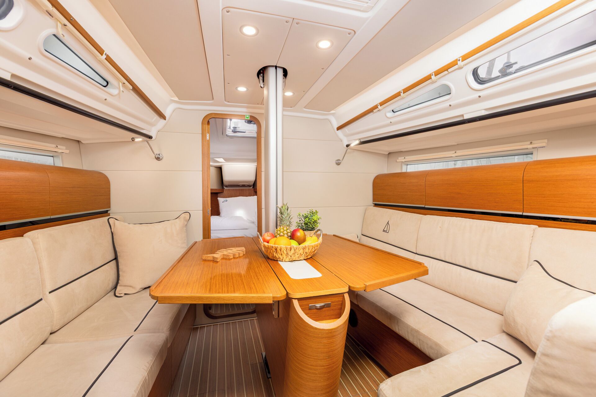 Un espacio interior compacto con una mesa central, asientos acolchados y un ventanal pequeño.