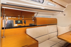 Interior de uma motorhome compacta, com painel de madeira, painel de controle e área de estar acolchoada.