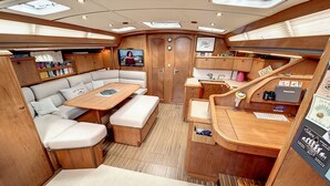 A compact interior with a sofa, a table, a small kitchen area, and a television. - Sun-Kissed Sailing Adventure in Cataluña (Rosas / Roses)