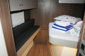 A compact bedroom with a bed, a small sofa, and a wardrobe. - Dubrovnik Delight: A Sun-Kissed Sailing Experience (Komolac)