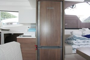 A compact room with a wooden door, a small kitchenette, a bed with striped bedding, and a view of a mountainous landscape. - Dubrovnik Delight: A Sun-Kissed Sailing Experience (Komolac)