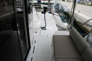 A boat deck with a cushioned seating area, a steering wheel, and various ropes and equipment. - Dubrovnik Delight: A Sun-Kissed Sailing Experience (Komolac)