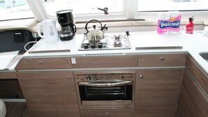 A compact kitchen with a built-in oven, a coffee maker, and a kettle on the countertop. - Dubrovnik Delight: A Sun-Kissed Sailing Experience (Komolac)