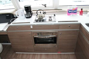 A compact kitchen with a built-in oven, a coffee maker, and a kettle on the countertop. - Dubrovnik Delight: A Sun-Kissed Sailing Experience (Komolac)