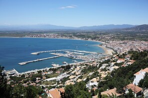 A coastal cityscape with a marina, residential areas, and mountains in the background.