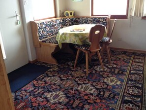 Ein Zimmer mit einer Sitzgruppe, einem Tisch mit Tischdecke und gemusterten Teppichen.