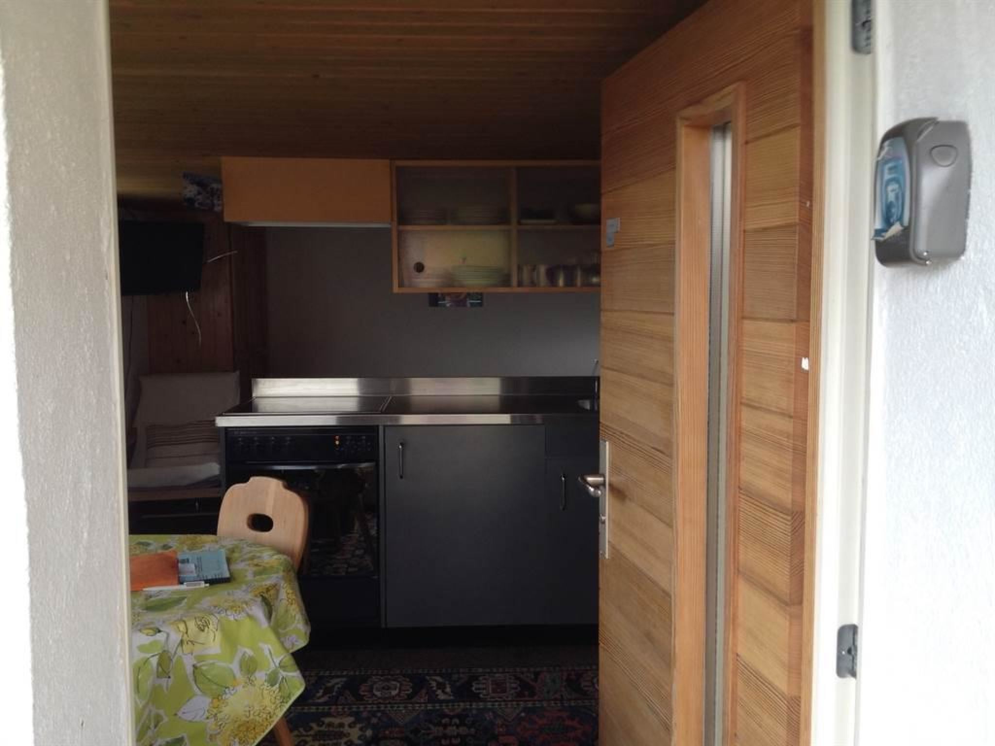 A compact kitchen with a refrigerator, a sink, and a small dining area with a table and chair.