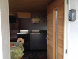 Eine kleine Küche mit einem Kühlschrank, einem Spülbecken und einer Essecke mit Tisch und Stuhl.