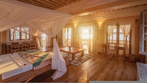 Una habitación con cama, una mesa y una silla, con vista al mar a través de amplios ventanales.
