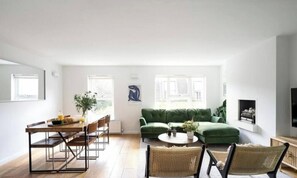 A spacious living room with a green sofa, a dining table with chairs, and a fireplace. - The Portobello Hideaway 2 Beds (London)