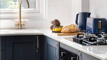 A modern kitchen with dark cabinets, a gold faucet, and a window providing natural light.