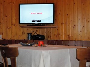 A conference room with a table, chairs, a television displaying 'WELCOME', and a wooden wall.