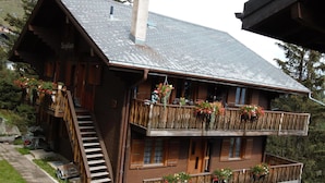 Eine Holzhütte mit Balkon, Treppe und Blumenkästen.