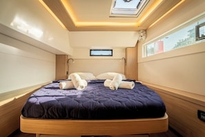 A modern hotel room with a bed, skylight, and a small window.