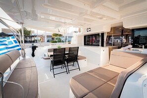 A yacht's deck with a dining area, seating, and a view of the marina. - Sun-Kissed Sailing Adventure in the Stunning Islas Cícladas (Paros)