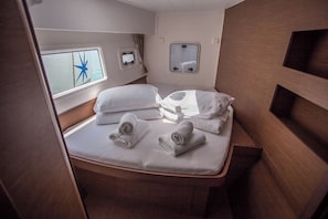 Een compacte, goed verlichte hutkamer met een enkel bed, een klein raam met sterrenversiering, en een spiegel.