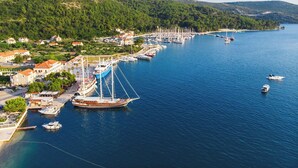 Un port marítim costaner amb vaixells, un gran veler i edificis al llarg de la riba.