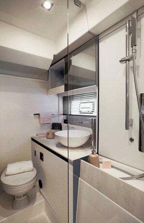 Un baño moderno con un espejo grande, un lavamanos blanco, un inodoro y una ducha.