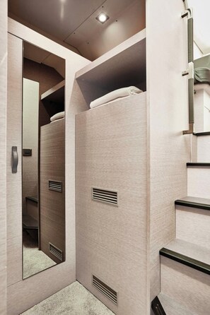 Ein kleines, modernes Badezimmer mit Spiegel, Handtuchhalter und Lüftungsgittern.