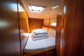 Ein gemütliches Blockhaus mit Dachfenster, einem Bett mit Kissen und einer kleinen Ablagefläche.