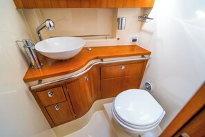Een kleine badkamer met een witte wastafel, een houten opbergmeubel en een toilet.