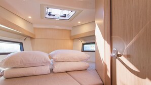 Een compacte, goed verlichte kamer met een bed, dakraam en een deur.