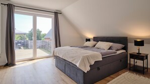 Une chambre avec un lit, une table de chevet et une vue sur le jardin à travers une porte coulissante.